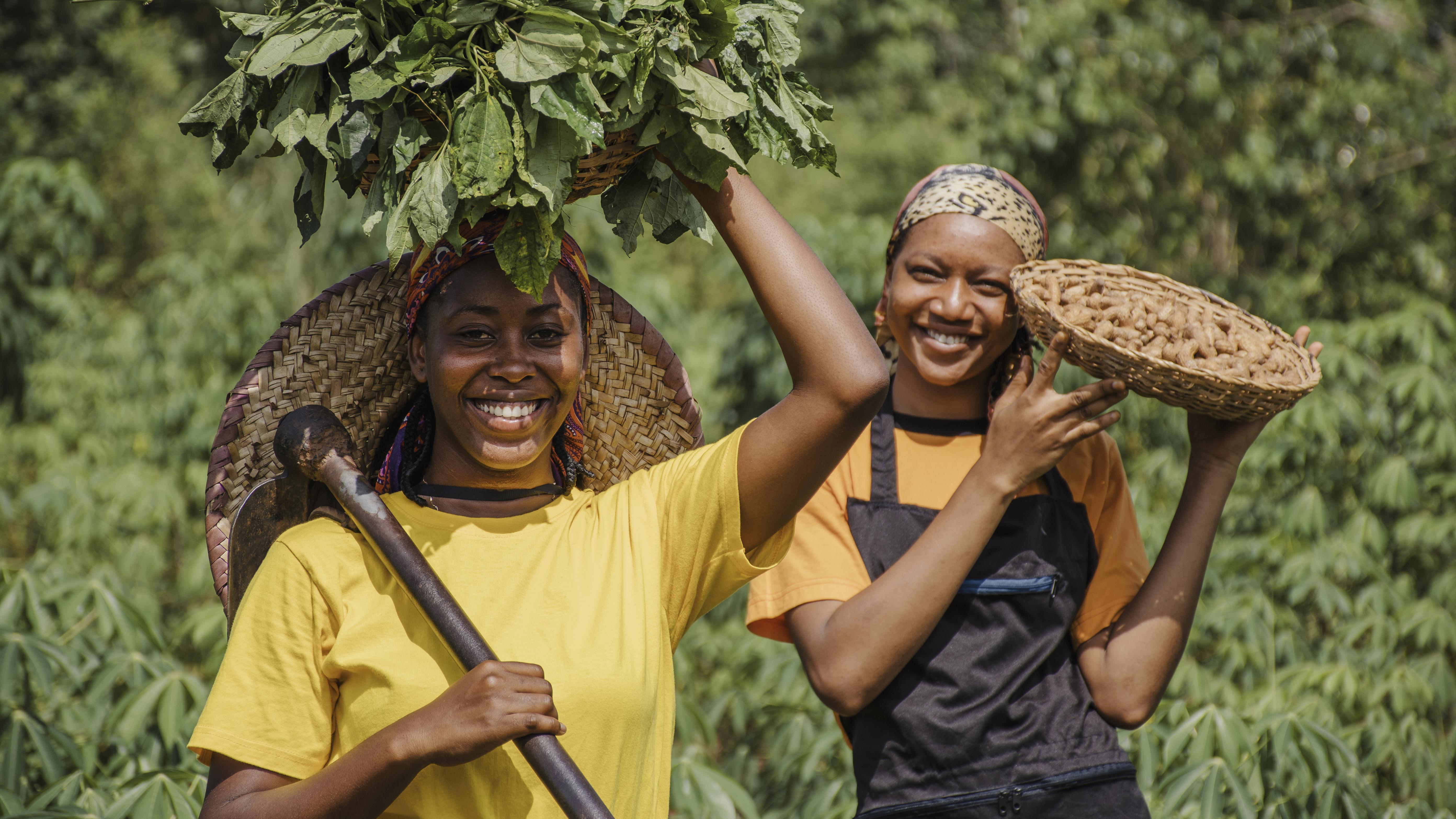 African women farmers proudly holding their harvest in a lush green field